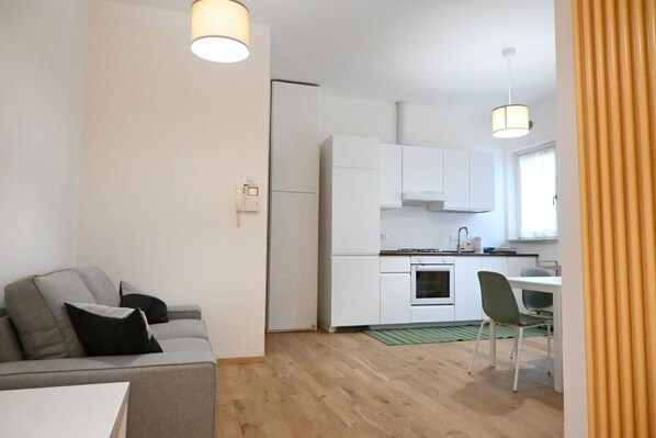 A compact living space with a kitchenette, a sofa, a dining area, and a window.