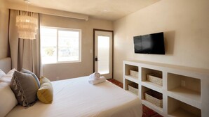 Une chambre d’hôtel avec un lit, un téléviseur fixé au mur et une fenêtre avec des rideaux.