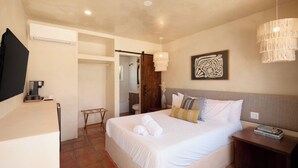 Une chambre à coucher avec un lit, une table de chevet et un téléviseur posé sur un meuble.