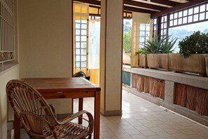 Une pièce avec une table et une chaise en bois, une fenêtre donnant sur un paysage verdoyant et un sol carrelé.