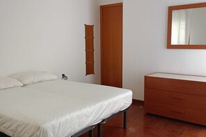 Un dormitorio con una cama, un aparador de madera, un espejo y una puerta.