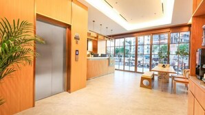 A modern hotel lobby with a reception desk, a seating area, and large windows offering a view of the city. - Super 8 Preferred Hotel（Mentougou Xinqiao Street Branch Conversion） (Beijing)