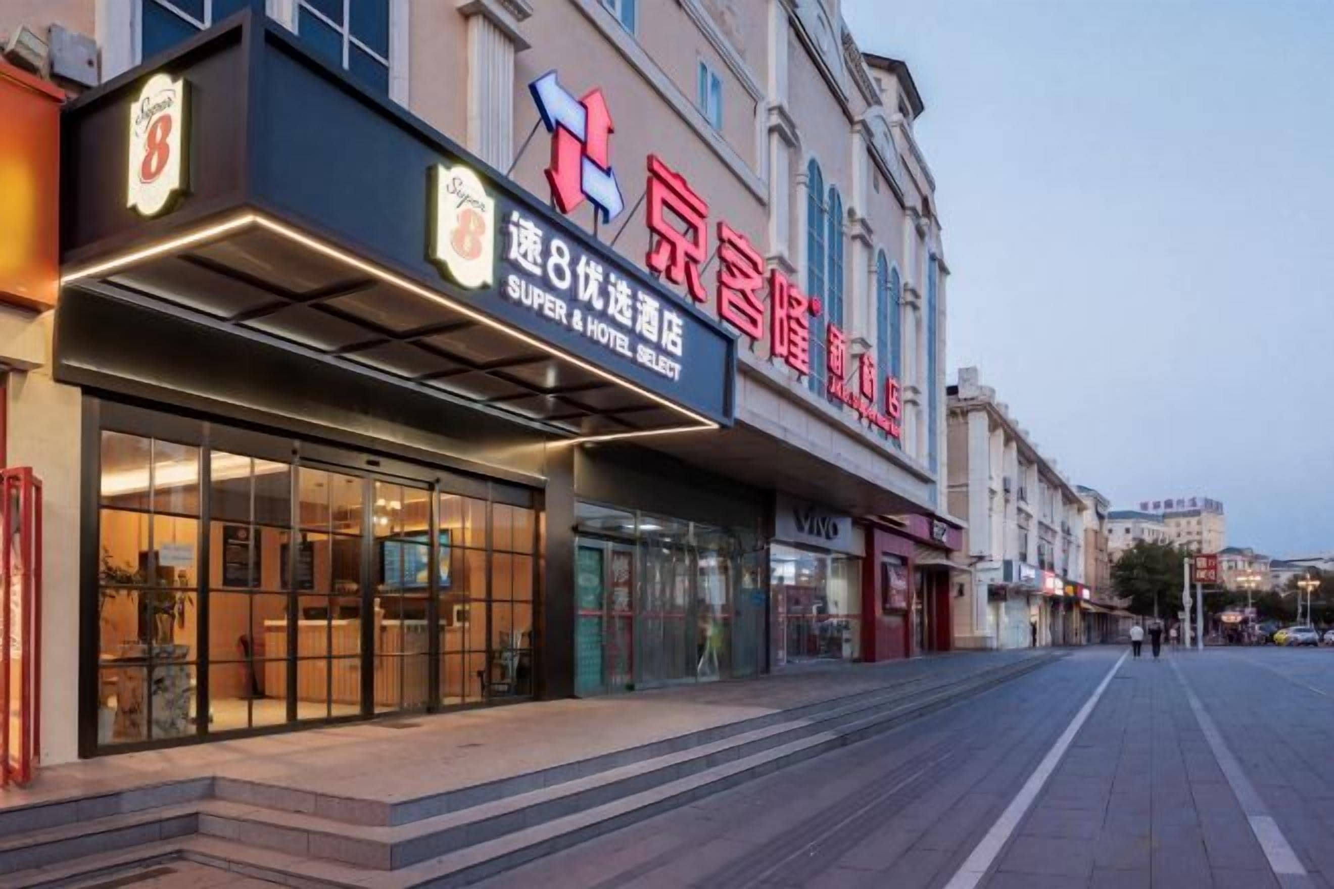 A hotel with a prominent sign, a covered entrance, and a clear view of the street.