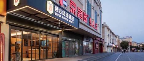 A hotel with a prominent sign, a covered entrance, and a clear view of the street.