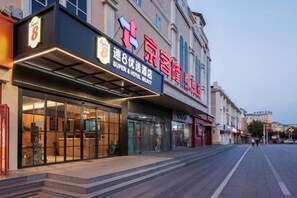 A hotel with a prominent sign, a covered entrance, and a clear view of the street.