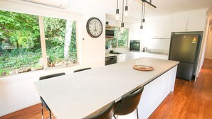 A modern kitchen with a large island, white cabinetry, a built-in oven, and a refrigerator. - Lumley Vibes - Family haven in Bright (Bright)