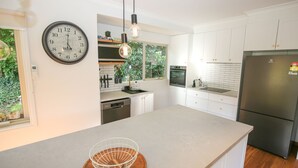 A modern kitchen with white cabinetry, a stainless steel refrigerator, a built-in oven, and a large island with a sink. - Lumley Vibes - Family haven in Bright (Bright)
