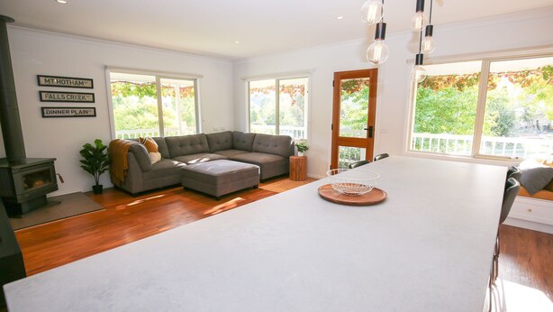 A modern living room with a sectional sofa, a dining area, and a wood-burning stove. - Lumley Vibes - Family haven in Bright (Bright)