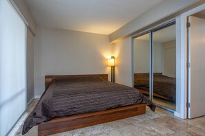 A bedroom with a bed, a bedside lamp, and a sliding glass door leading to a bathroom.