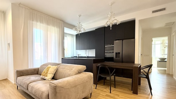 A modern living room with a sofa, a dining table, and a kitchen area with dark cabinets and stainless steel appliances. - SE156 – Senigallia, three-room apartment a few steps from the sea (Senigallia)