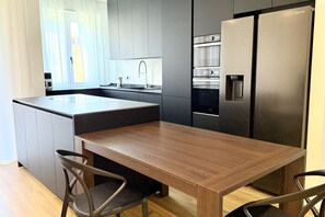 Eine moderne Küche mit Kochinsel, Edelstahlgeräten und einem Essbereich mit Holztisch und Stühlen.