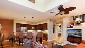 A modern living room with a dining area, kitchen, and a TV.