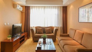 A living room with a sofa, a coffee table, a TV, and an air conditioning unit. - Xuting Hotel (Taiyuan Xinmin North Street) (Taiyuan)