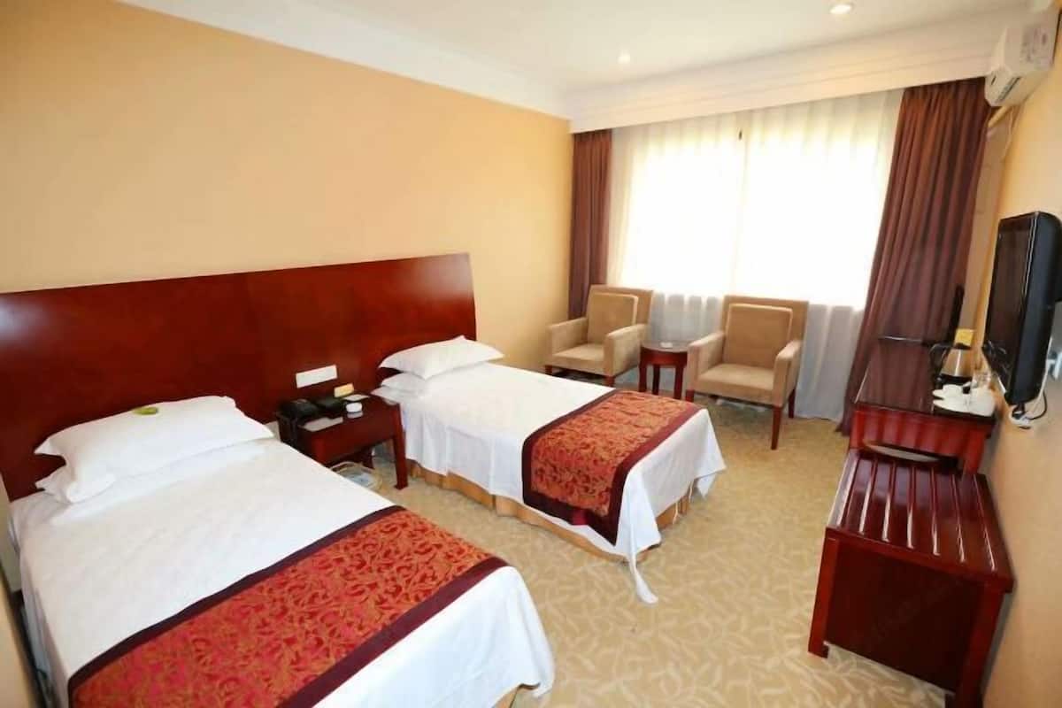 Une chambre d’hôtel avec deux lits, une télévision, un bureau et une chaise.