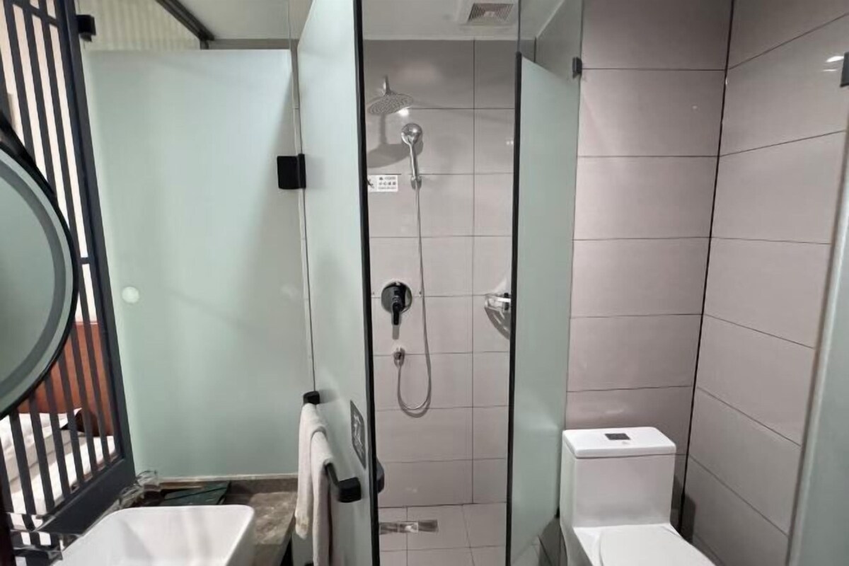 A modern bathroom with a glass-enclosed shower, a toilet, and a sink.