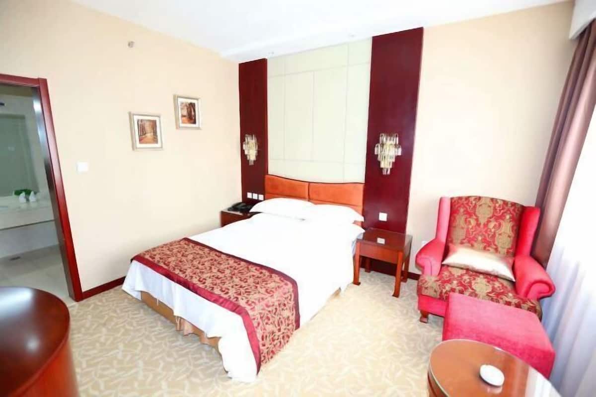 Une chambre d’hôtel avec un grand lit, une chaise, un bureau et un miroir.