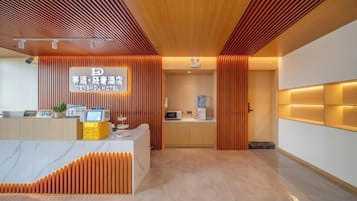 Zona de recepción de un hotel con diseño moderno, que incluye un mostrador de recepción, un sistema de registro digital y un espacio limpio y bien iluminado.