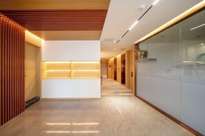 A modern hotel corridor with a reception area, wooden paneling, and a glass wall. - Overhere Light Luxury Hotel (Shanghai Wujiaochang Fudan University) (Shanghai)