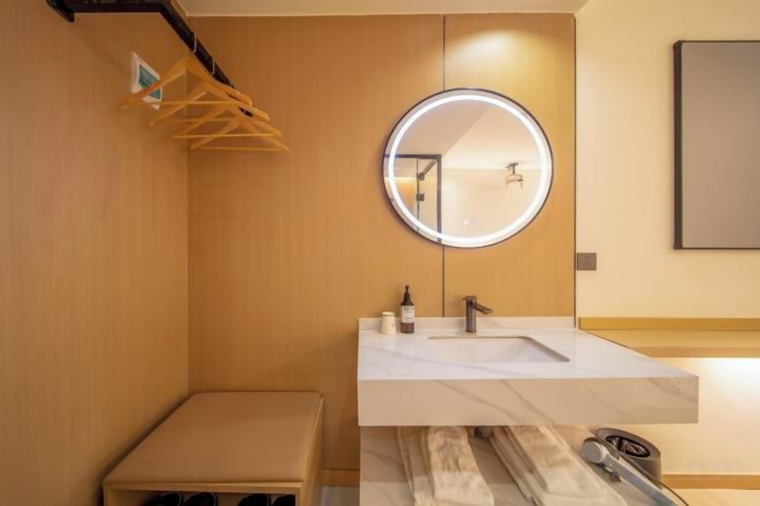 A modern bathroom with a round mirror, a sink, and a towel rack.