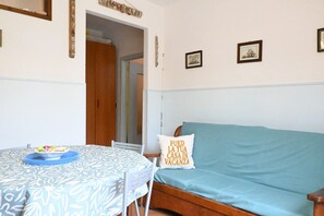A room with a bed, a table with a bowl, and a wall with a pillow.
