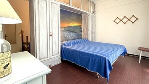 A bedroom with a bed, a wardrobe, a lamp, and a wall with geometric decor. - P054 - Porto Recanati, comfortable three-room apartment with outdoor patio (Porto Recanati)