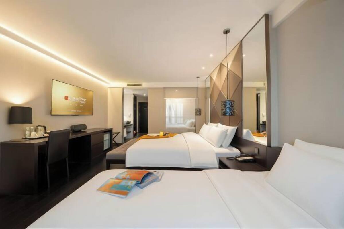 A modern hotel room with a large bed, a desk, and a TV.