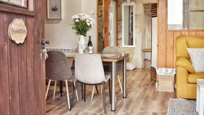 A cozy room with a wooden ceiling, a dining table with chairs, a sofa, and a small rug.