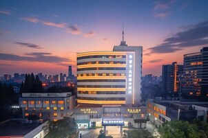 Un hotel de varios pisos con un atrio central, rodeado de otros edificios, durante el crepúsculo.