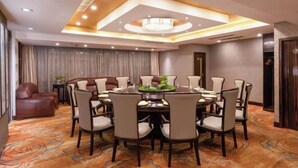 Un salón de conferencias con una mesa redonda, sillas y una araña.