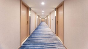 Un pasillo de hotel con alfombra azul, puertas de madera e iluminación empotrada.