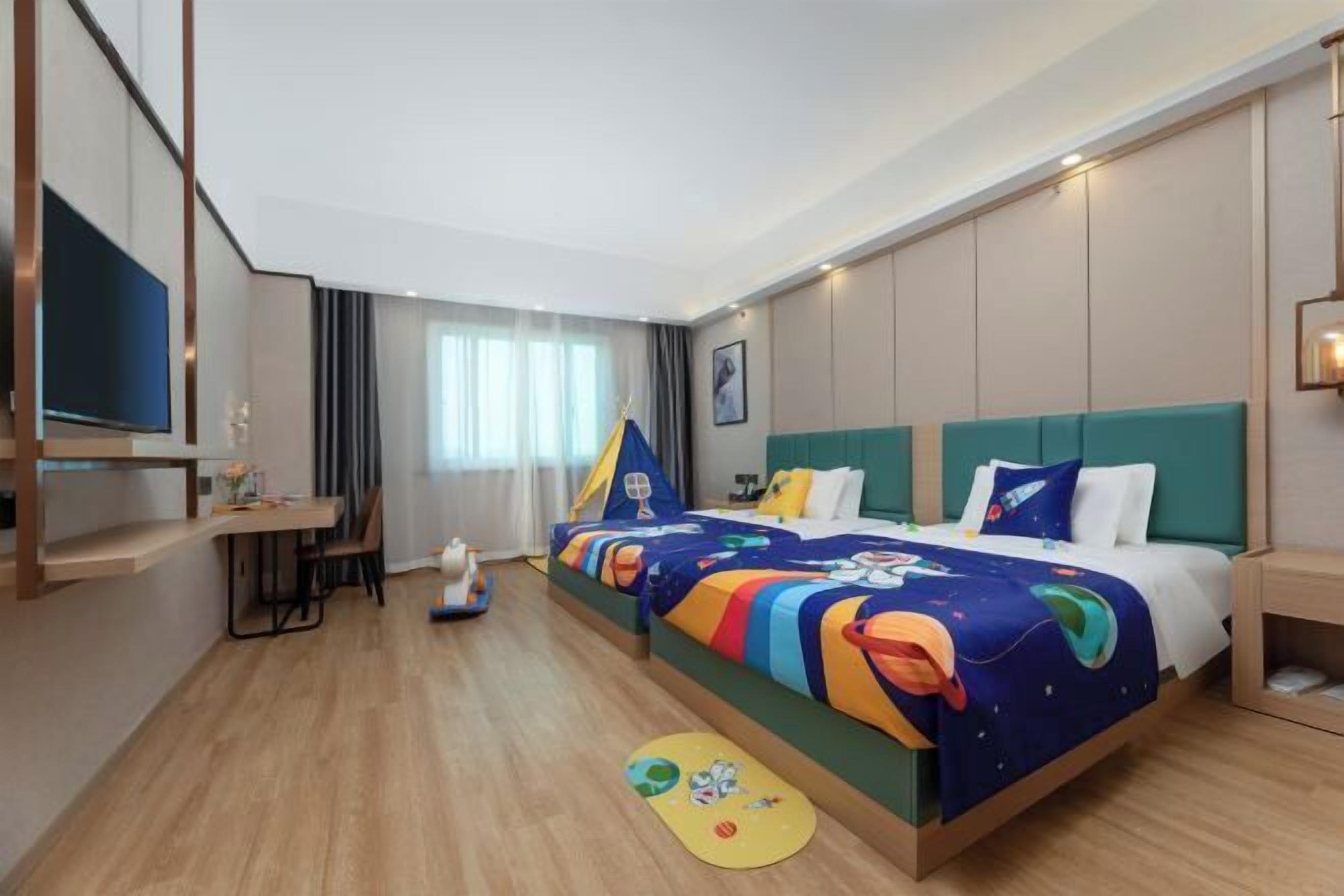 A hotel room with a large bed, a desk, a chair, and a television.