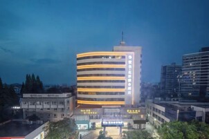 Un hotel de varios pisos con fachada curva, múltiples balcones y una entrada destacada con señalización.