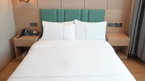 Habitación de hotel con una cama grande, dos mesitas de noche, una lámpara de pared y un panel de control.