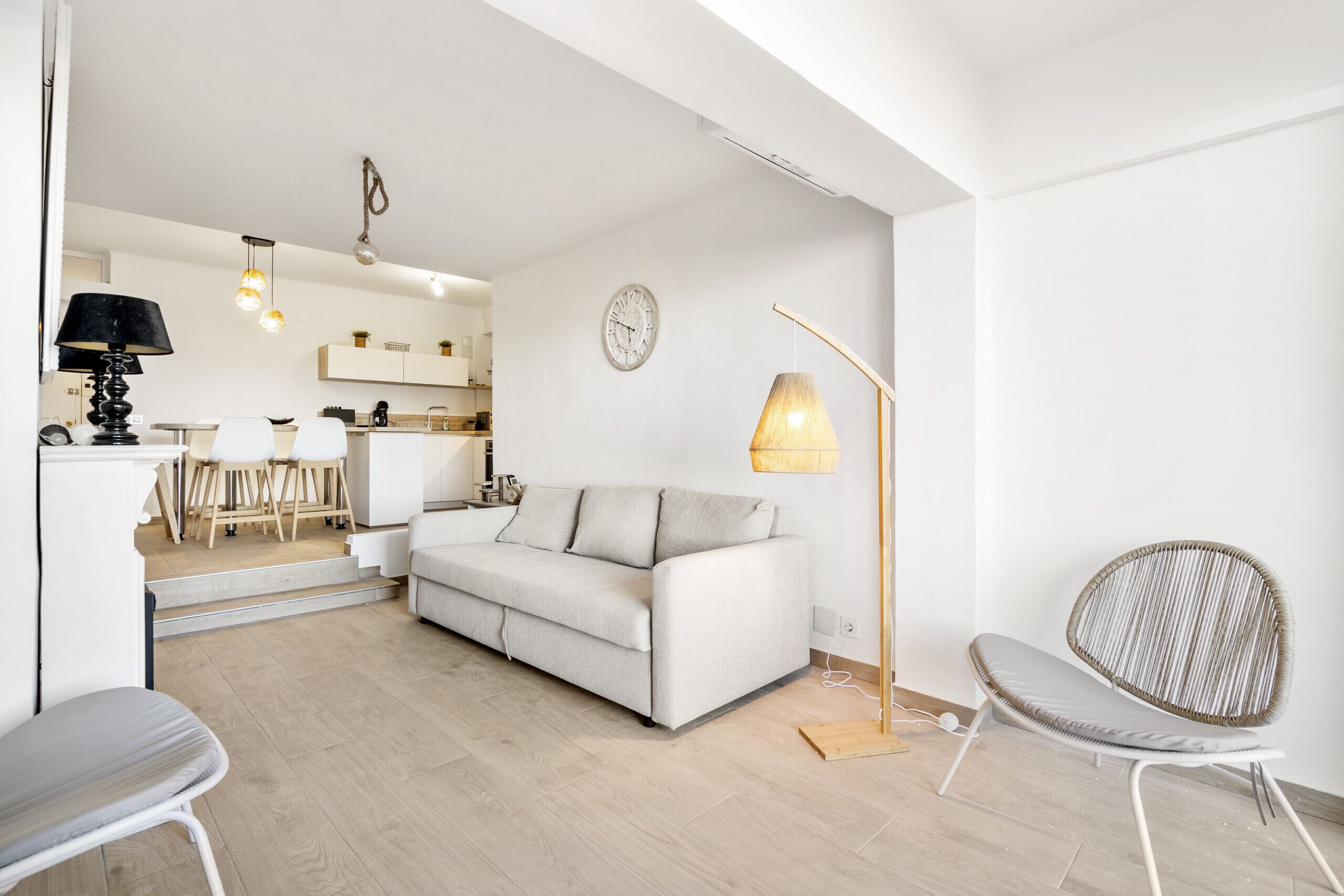 Een moderne woonkamer met een bank, een eethoek en een keuken op de achtergrond.
