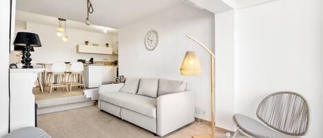 Een moderne woonkamer met een bank, een eethoek en een keuken op de achtergrond.
