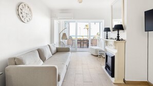 A living room with a sofa, a fireplace, a TV, and a balcony with a view. - WELCS APARTAMENTO 196 EMP  FRENTE AL MAR (Empuriabrava)