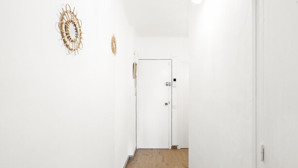A narrow hallway with a wooden floor and white walls. There is a door at the end of the hallway. - WELCS APARTAMENTO 196 EMP  FRENTE AL MAR (Empuriabrava)