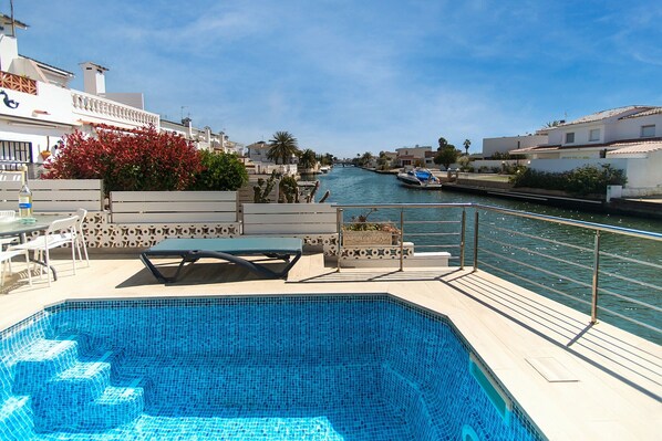 A swimming pool with a view of a canal and buildings in the background.