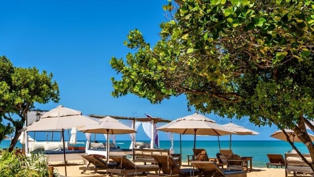 A beach with sun loungers and umbrellas, a clear blue sky, and a calm sea. - Terrazza Trancoso Hotel Boutique (Porto Seguro)