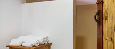 Una habitación con una mesa de madera, toallas, techo de madera y una puerta de madera.