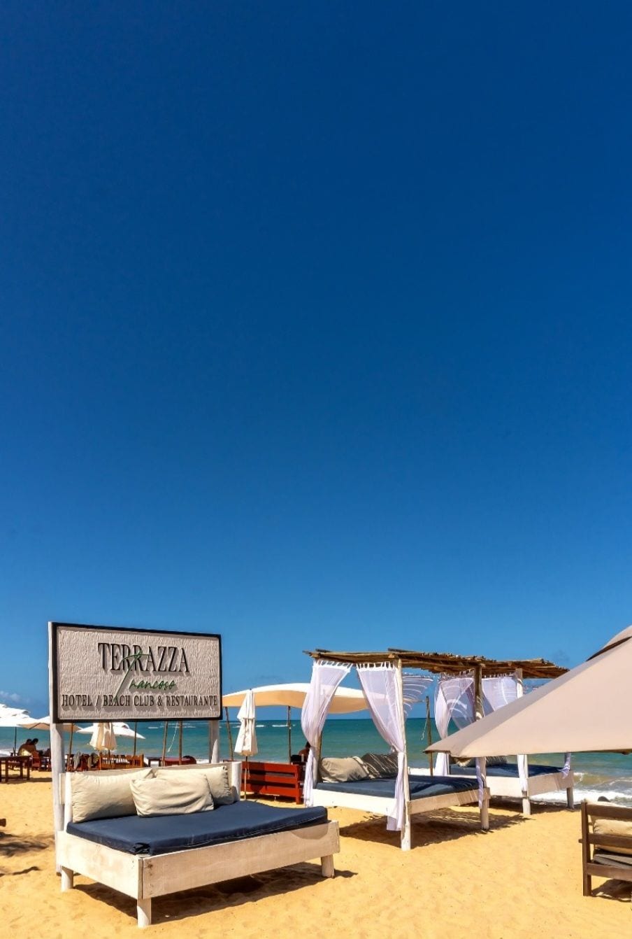 A beach setting with a sign for 'TERRAZZA Hotel & Beach Club & Restaurant'.