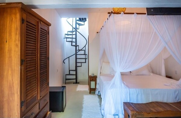 A bedroom with a bed under a canopy, a wooden wardrobe, and a spiral staircase. - Terrazza Trancoso Hotel Boutique (Porto Seguro)