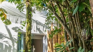 A pathway leading to a building surrounded by lush greenery and a bamboo fence. - Terrazza Trancoso Hotel Boutique (Porto Seguro)