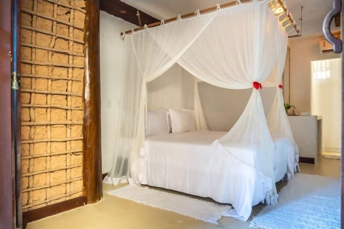 Une chambre à coucher avec un lit à baldaquin, du linge de lit blanc et un tapis blanc.