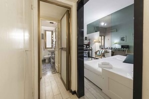 Une chambre d’hôtel avec un lit, une table de chevet, une lampe et une vue sur le couloir.