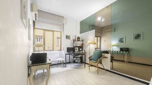 A room with a dining table, chairs, a sofa, a small side table, and a mirror. - Le Petit BSJ By MMega (Florence)