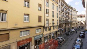 A multi-story building with a tea house on the ground floor, balconies, and parked cars on the street. - Le Petit BSJ By MMega (Florence)