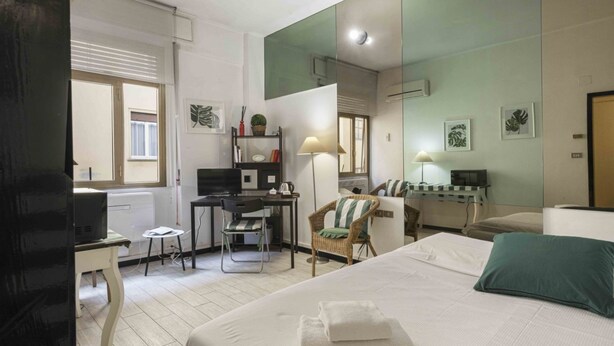 A hotel room with a bed, desk, chair, and a large mirror. - Le Petit BSJ By MMega (Florence)