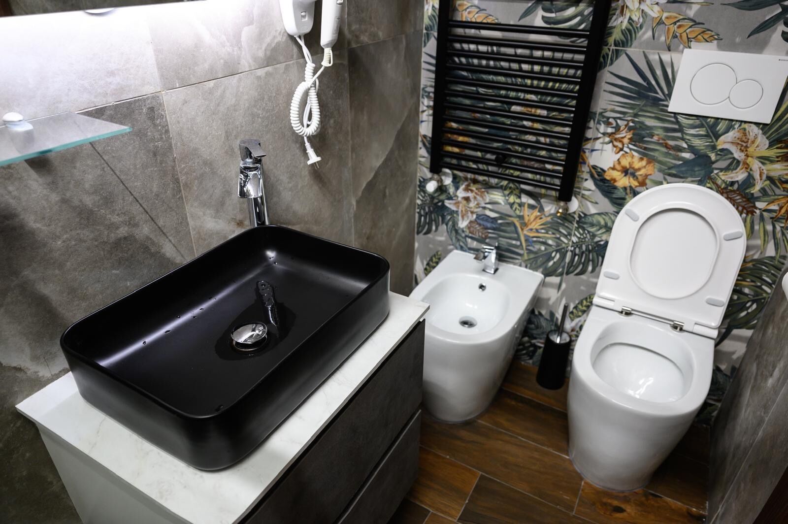Un baño con un lavamanos negro, un bidé y un inodoro.