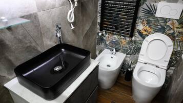 Un baño con un lavamanos negro, un bidé y un inodoro.
